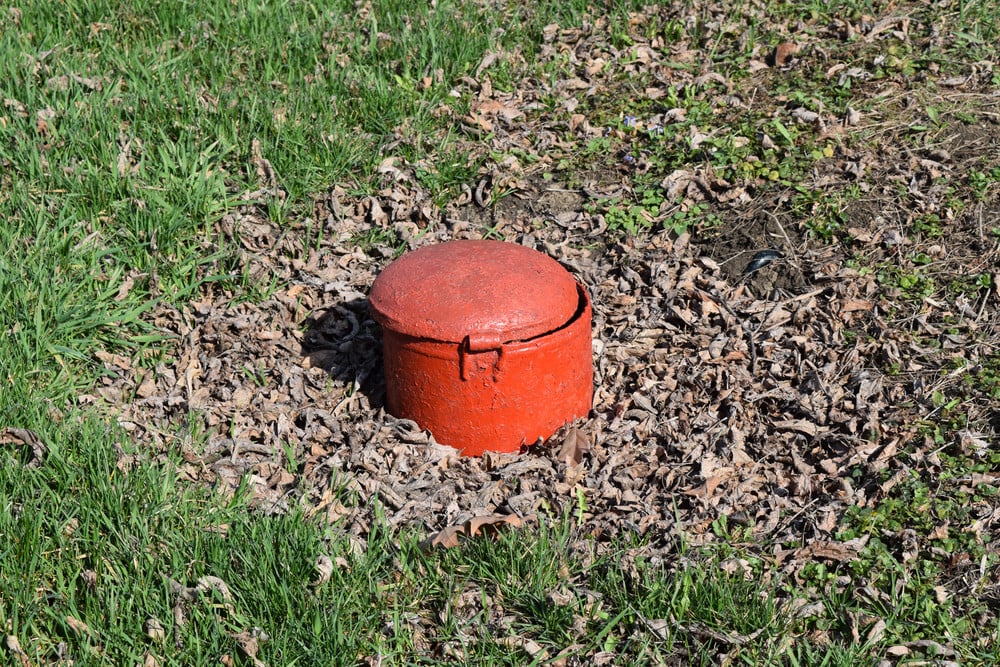 Red steel sewer hatch showing access to underground sewer lines and potential sewer line replacement.